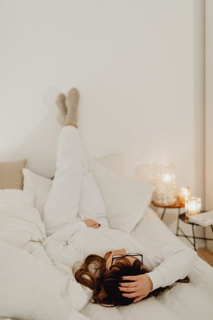 pexels-photo-6660833-6660833 Woman relaxing in a cozy, minimalist bedroom setting with warm lighting and soft textures.